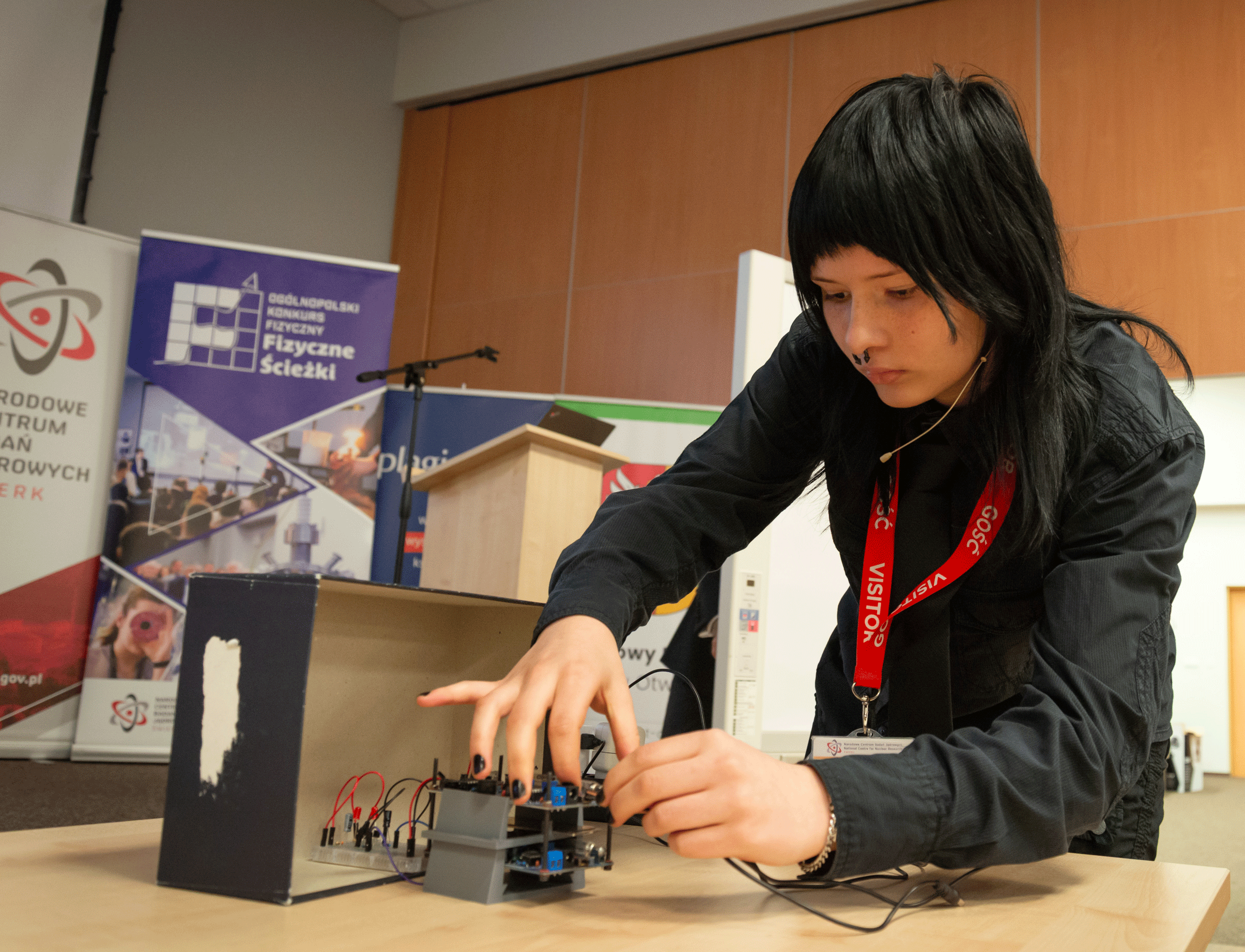 In the photograph, a student is performing a physics demonstration